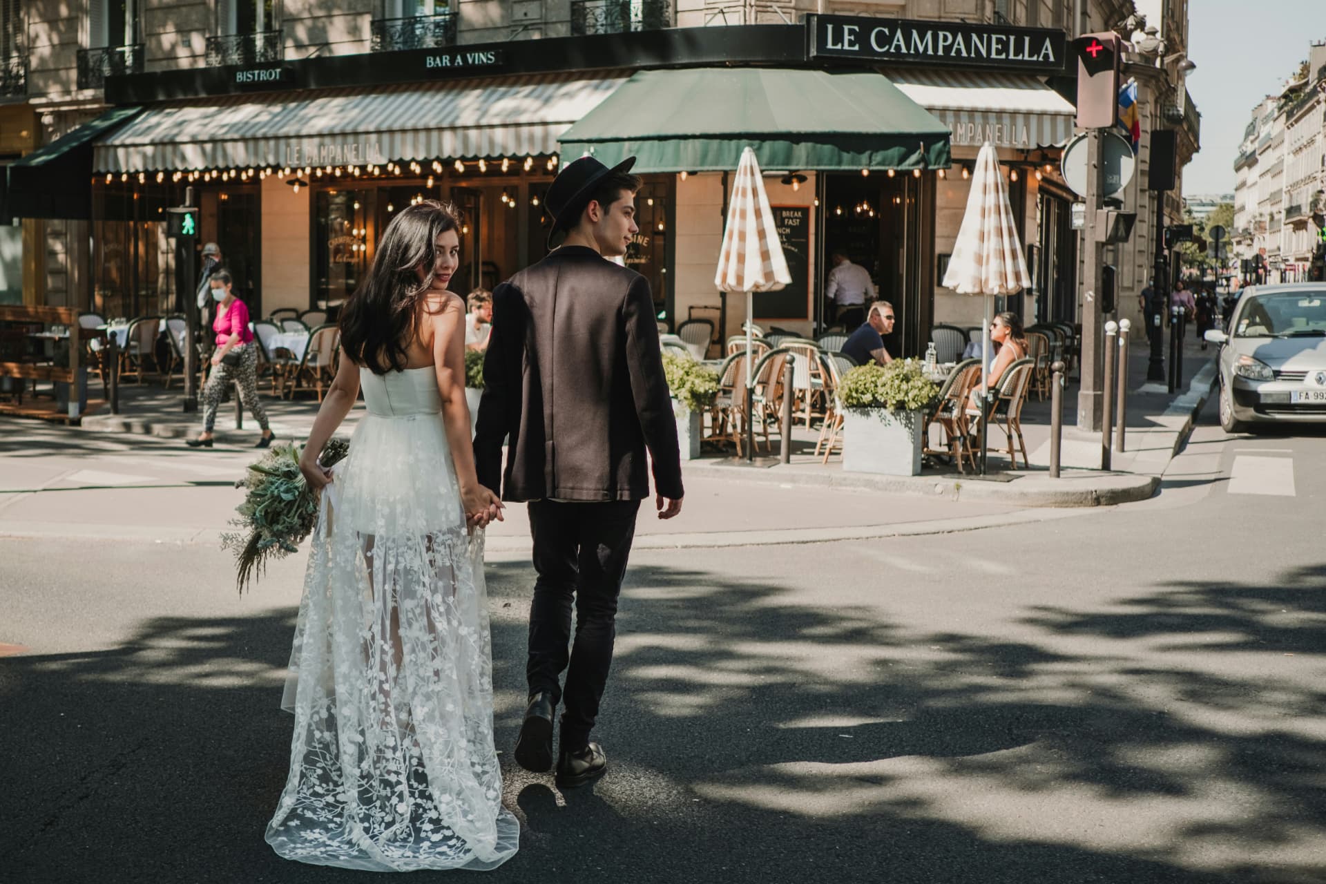 Novios cruzando la calle frente a un bistró parisino