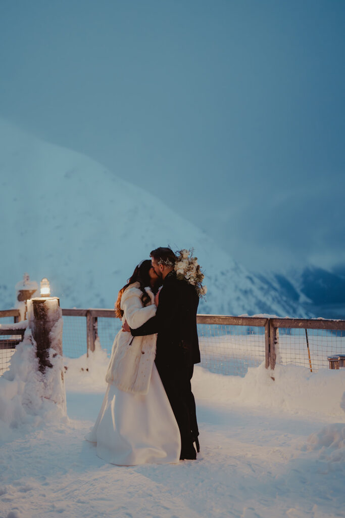 Beso de los novios frente a las montañas nevadas