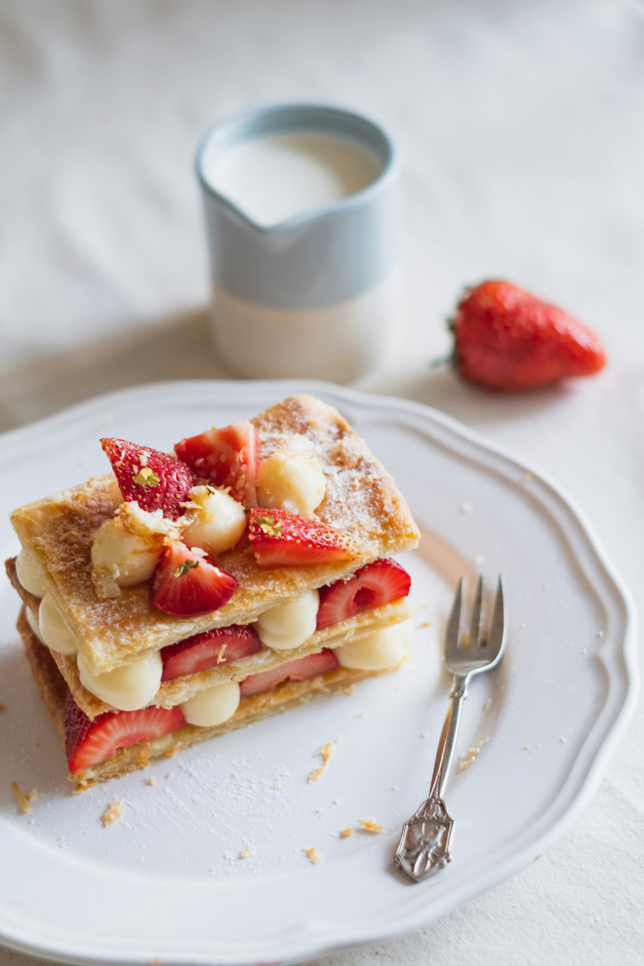 Mille-feuille de fresas con crema pastelera sobre plato blanco