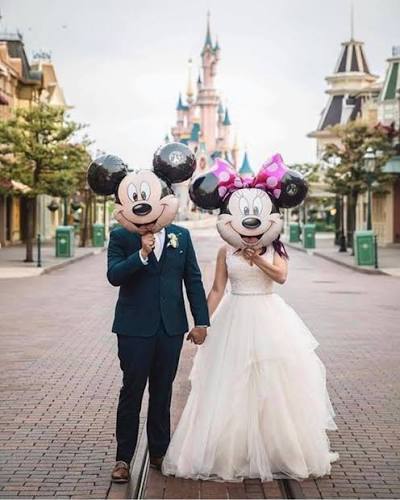 Novios con globos frente a un castillo de cuento