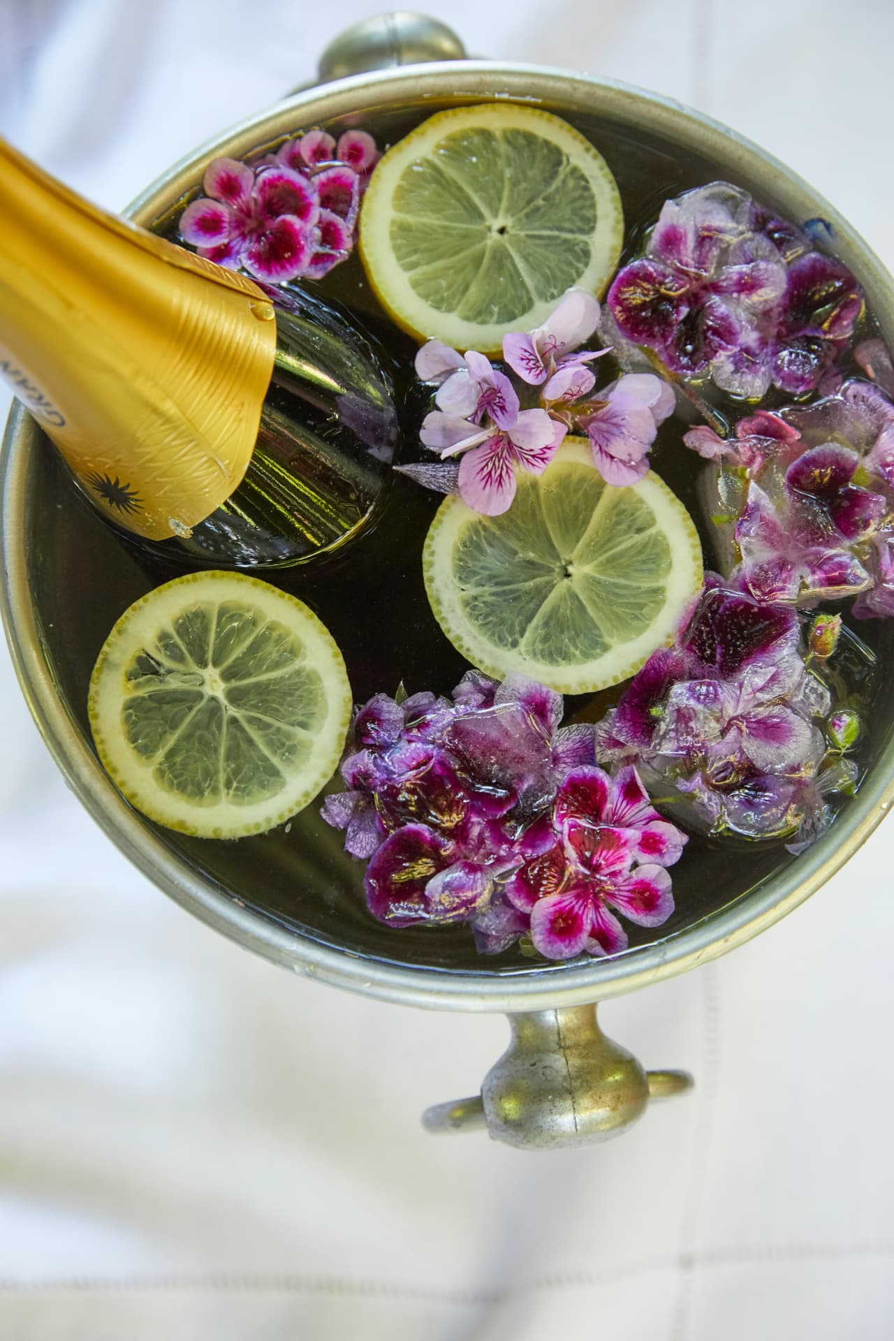 Botella de champán enfriando entre flores y limón